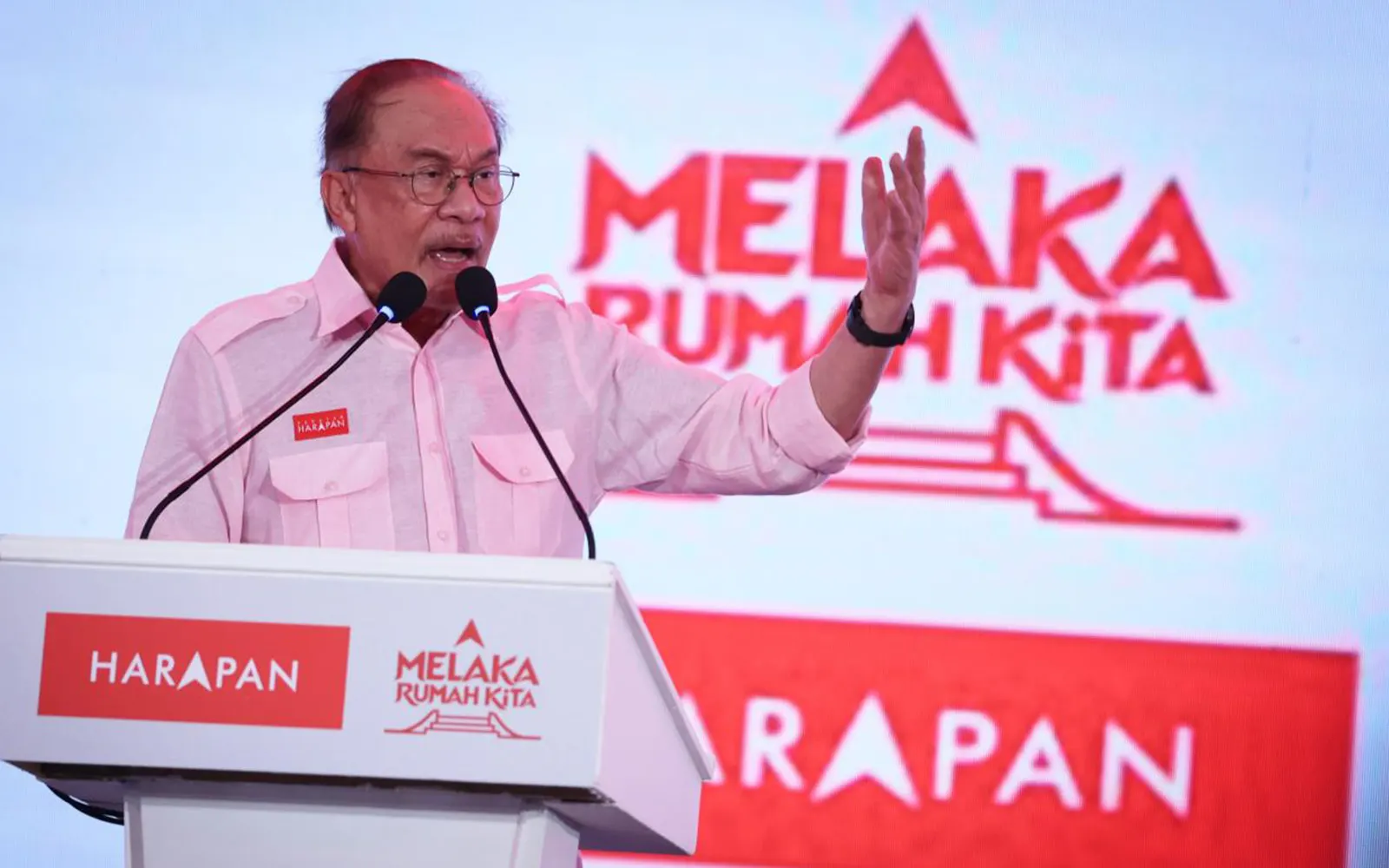 Anwar Ibrahim speaking at a Harapan podium in front of the Melaka Rumah Kita logo