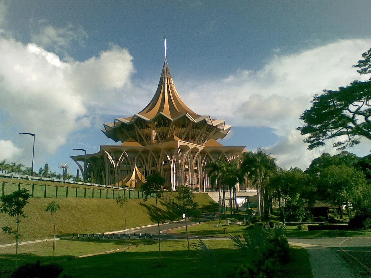 Bangunan Dewan Undangan Negeri Sarawak di Kuching dengan bumbung emas bertingkat, dilihat dari taman di bawahnya