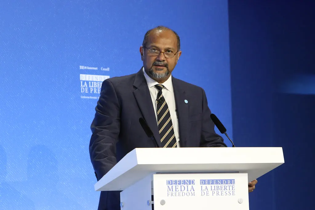 Gobind Singh Deo speaking at a podium at an international conference, against a blue backdrop