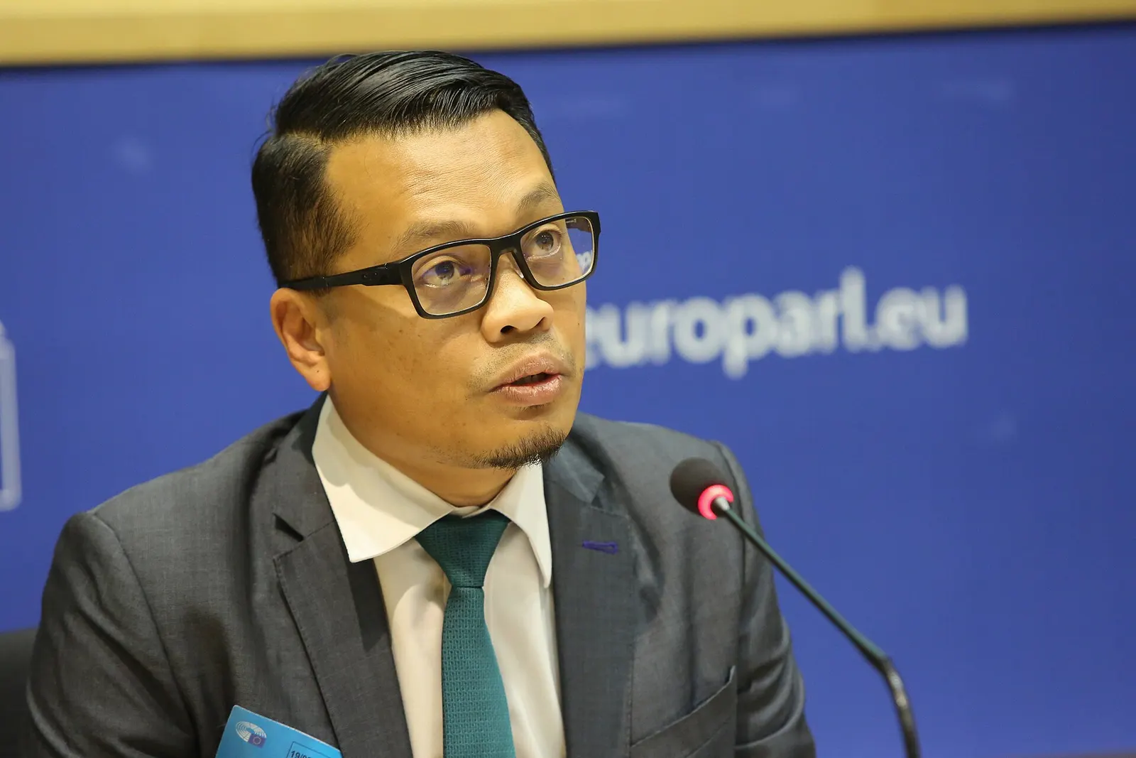 Nik Nazmi Nik Ahmad speaking at a microphone at a forum in the European Parliament in 2019