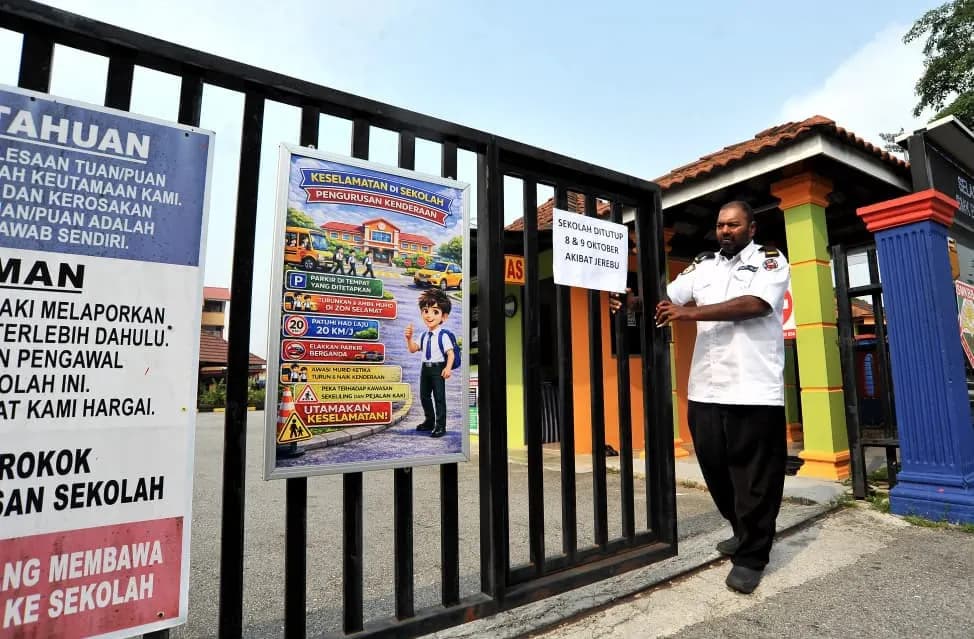 A security guard holds a notice that the school is closed on 8 and 9 October because of haze at a school gate, file photo
