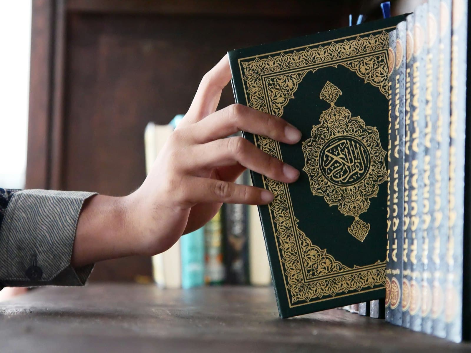 Tangan mengambil naskhah al-Quran berkulit hijau dari rak buku