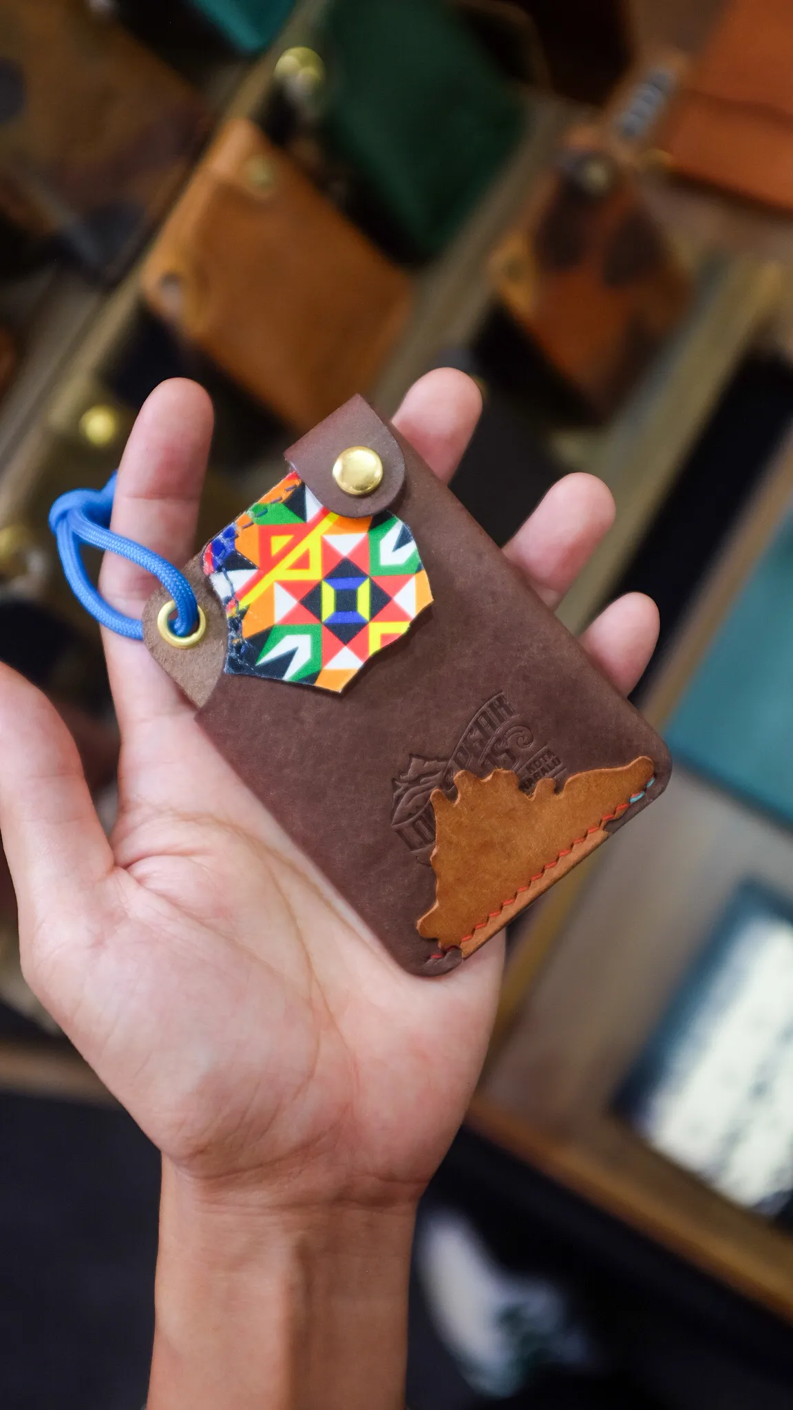 Pemegang kad kulit coklat dengan tampalan motif tradisional Sabah yang berwarna-warni dan bentuk Gunung Kinabalu