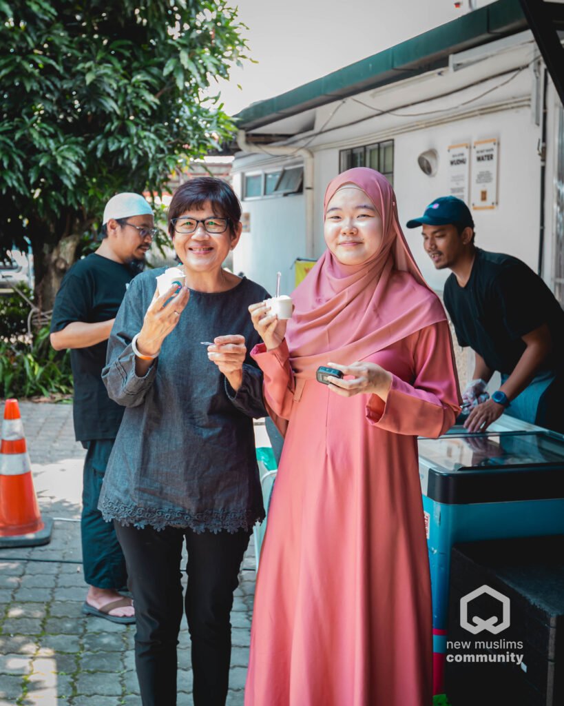 Dua pengunjung tersenyum sambil memegang cawan aiskrim semasa Hari Terbuka NMC sebelum ini